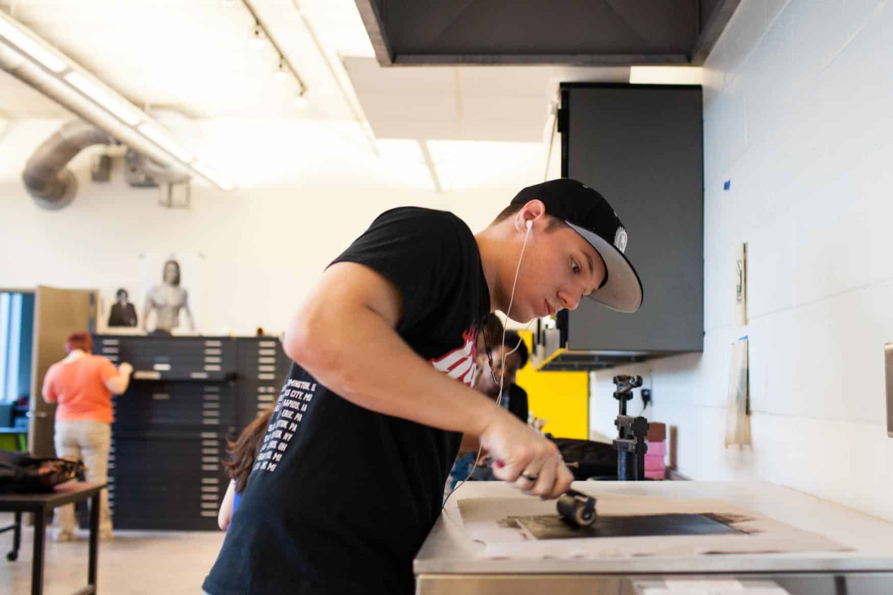 Young man wearing a hat working on screen printing in an art studio