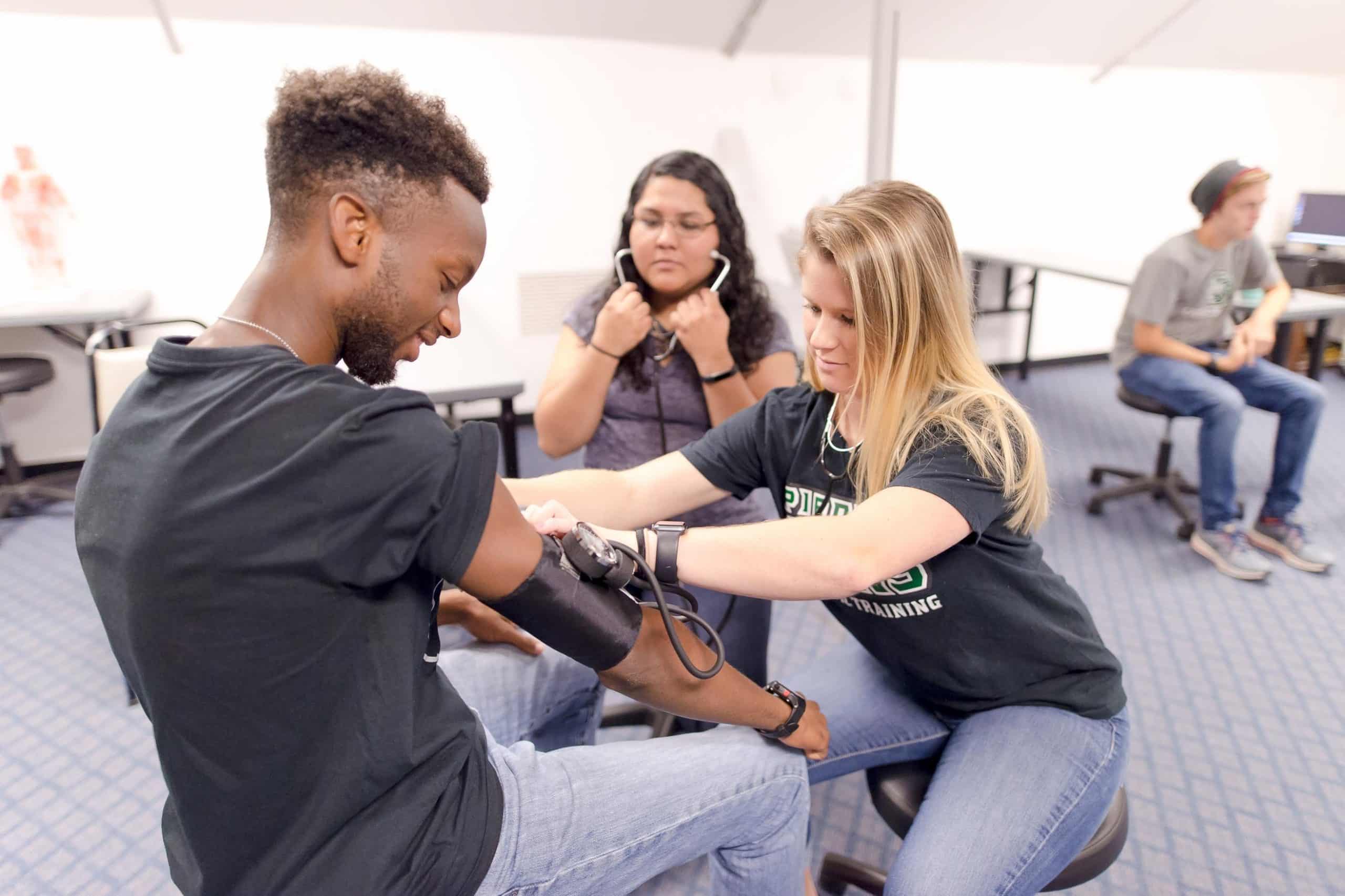 Three students learning how to take blood pressure.