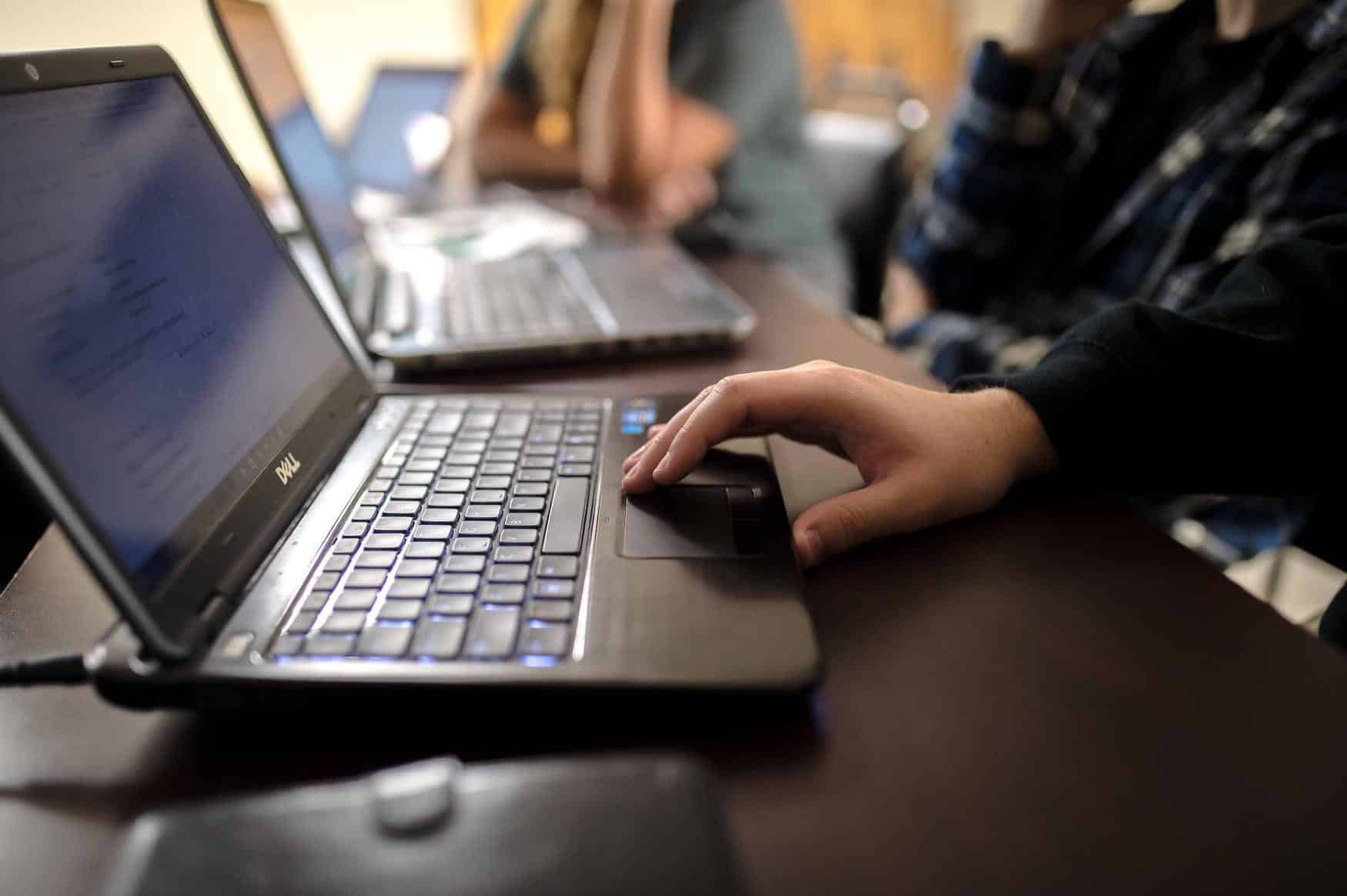 Zoomed in view of a persons hand while using the track pad of a laptop.