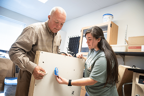 Professor and student measuring a piece of wood