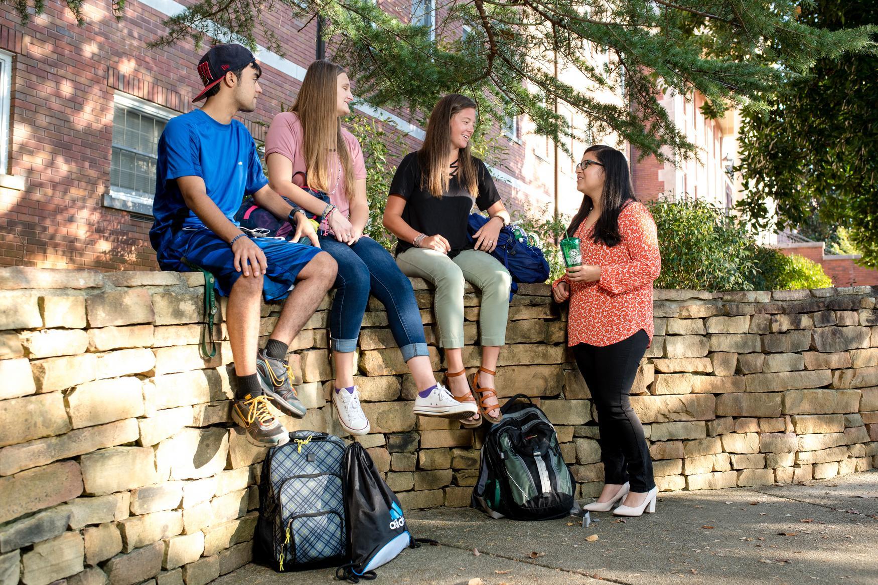 Group of students sitting on a rock wall