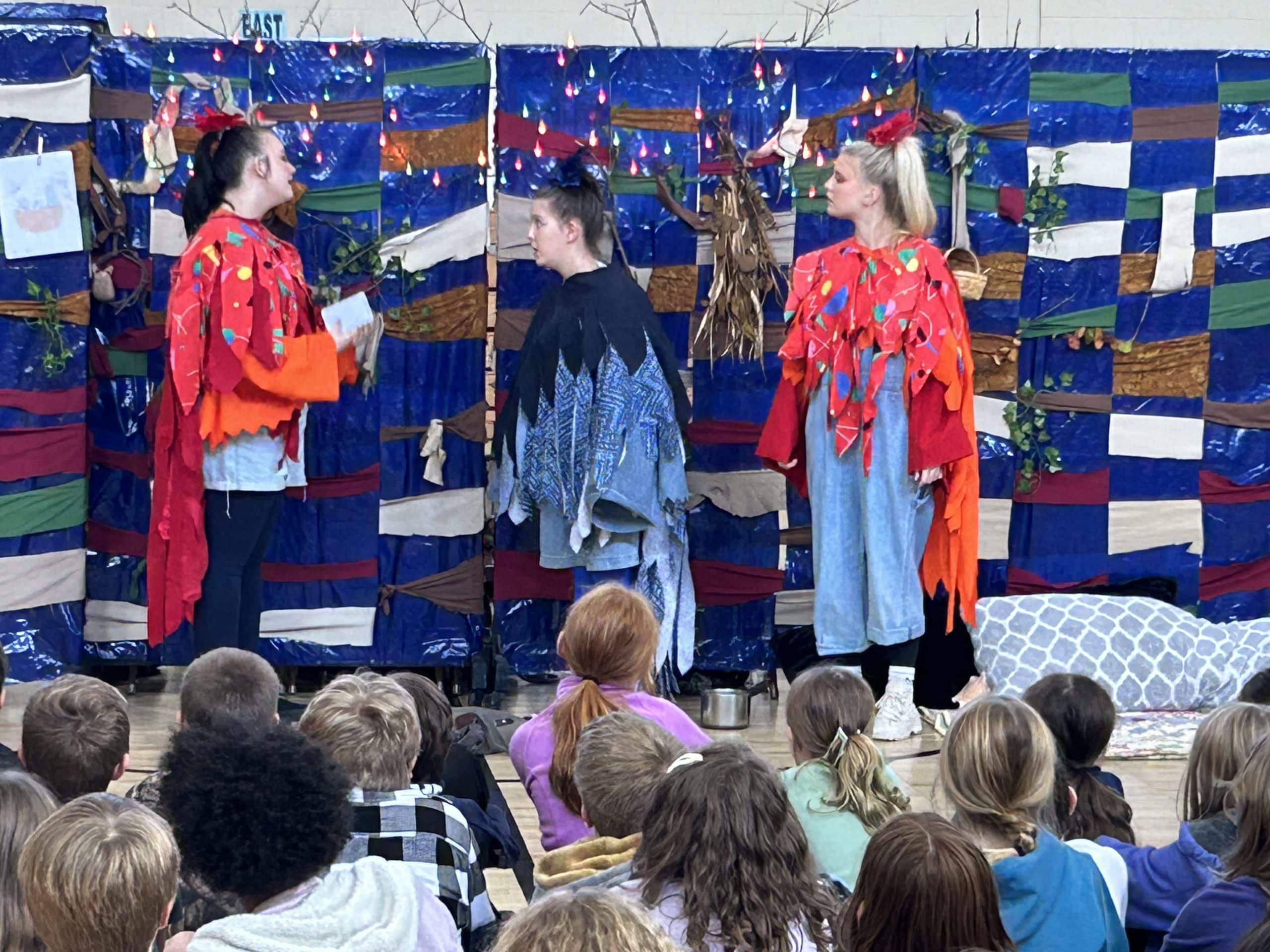 Three Piedmont students wearing costumes performing for a group of children