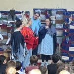 Four students in costume performing for a group of children