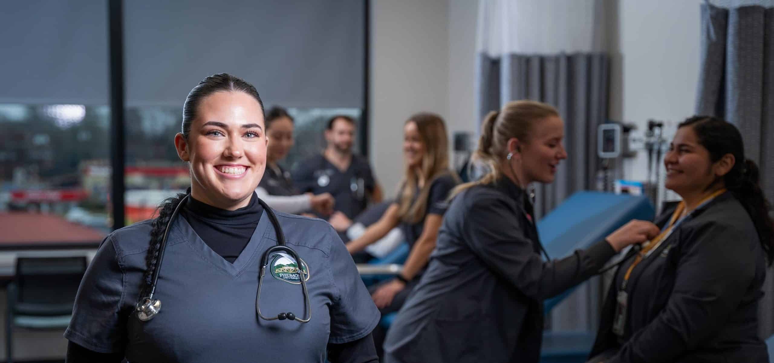 Nursing student smiling and posing for an image. In the background other nursing students are seen.