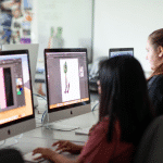 Side profile view of two students working on Mac computers