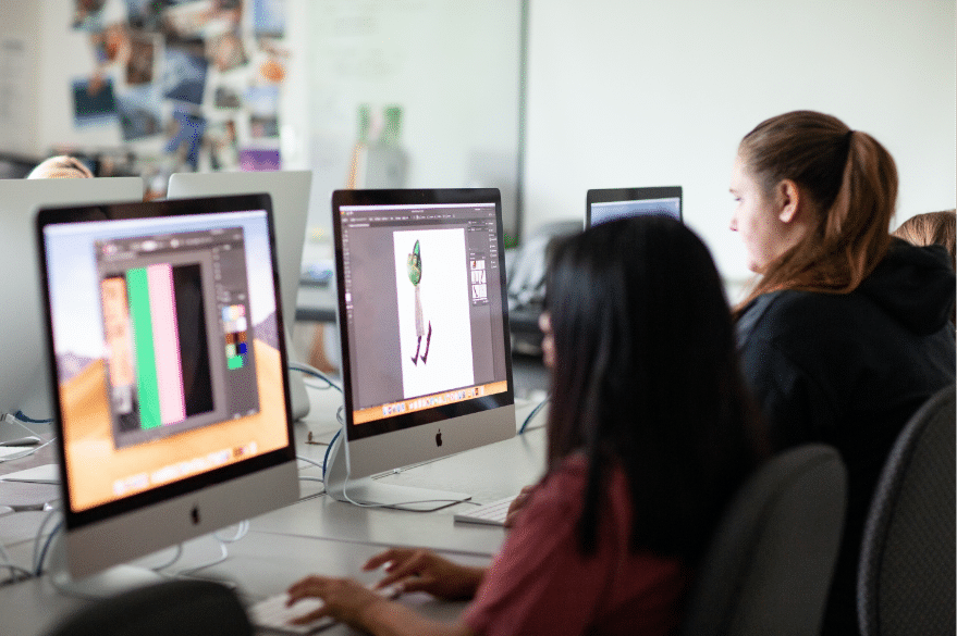 Side profile view of two students working on Mac computers