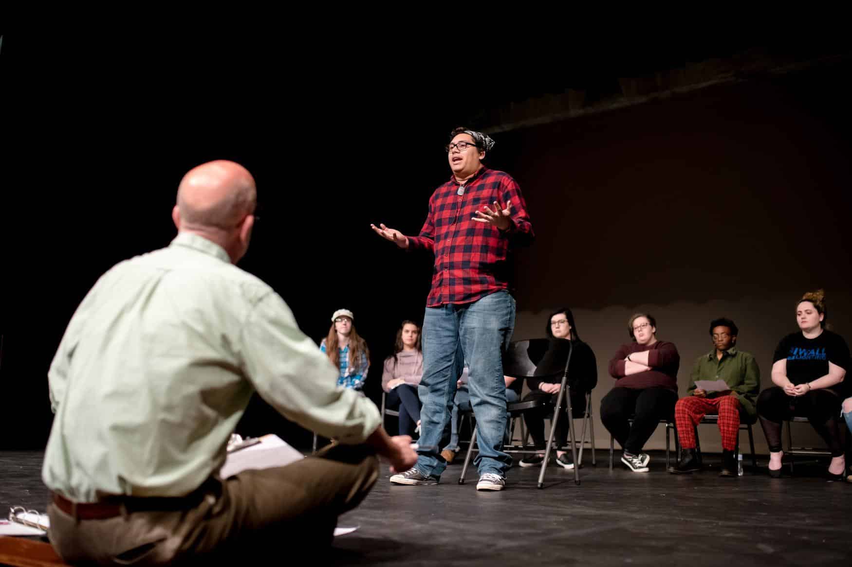 Group of students and professor acting out a dramatic scene.