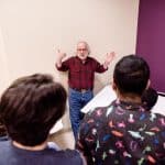 Professor wearing a red plaid shirt instructing a group of students