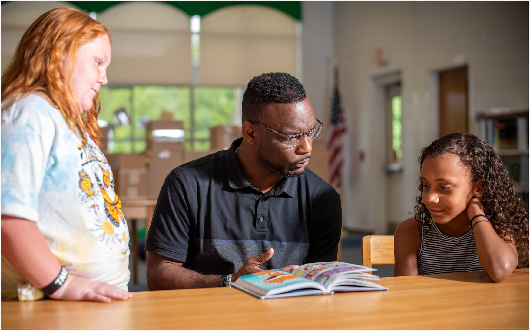 Young man reading and talking to two young children.