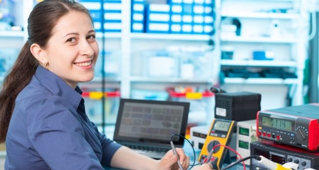 Woman smiling at the viewer, while holding engineering equipment.