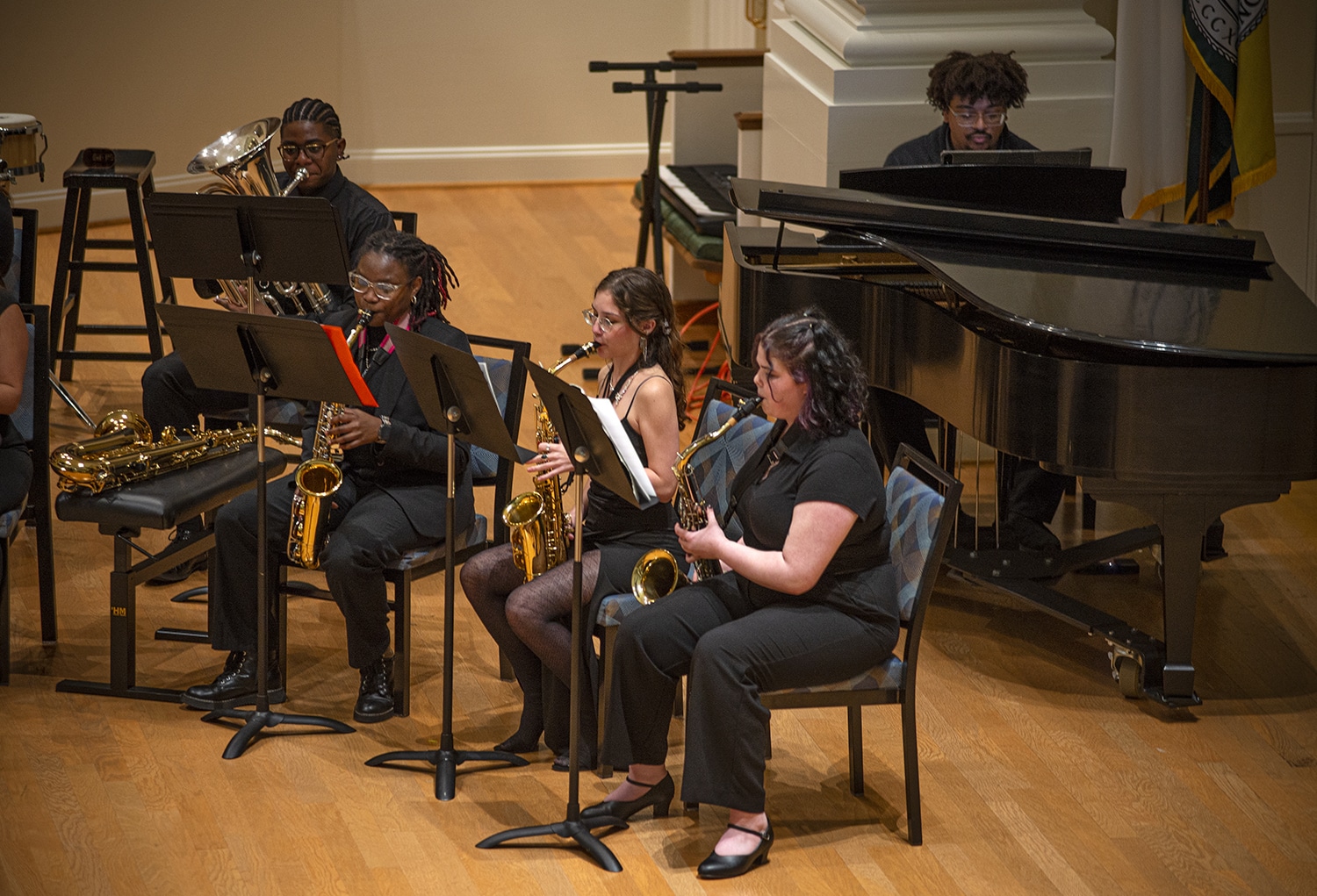 Group of students playing wind instruments, including saxophone, baritone, and piano