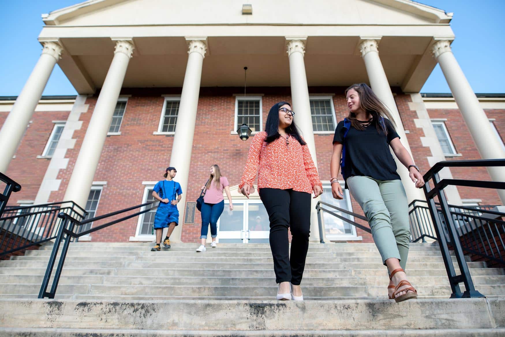 Group of students walking down the stairs in front of a building