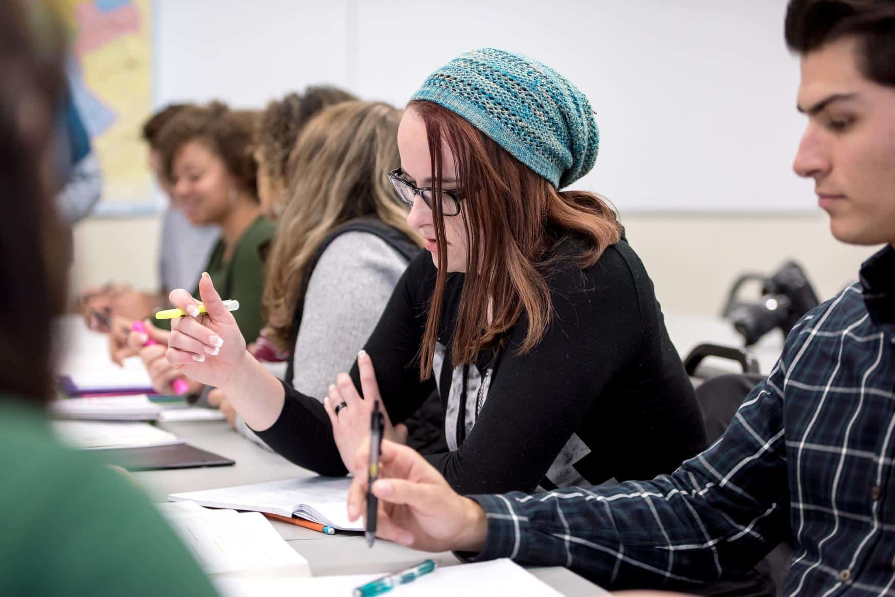 Row of students taking notes and writing on paper.