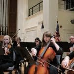 Musicians play string instruments in a performing hall.