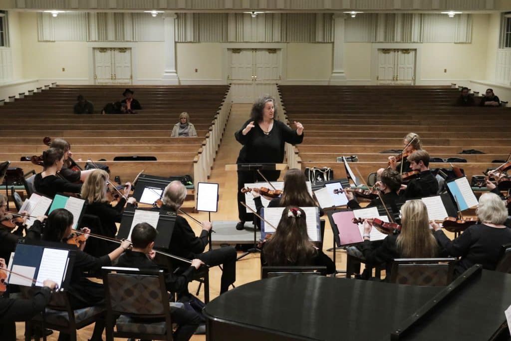 Female conductor leading musicians.