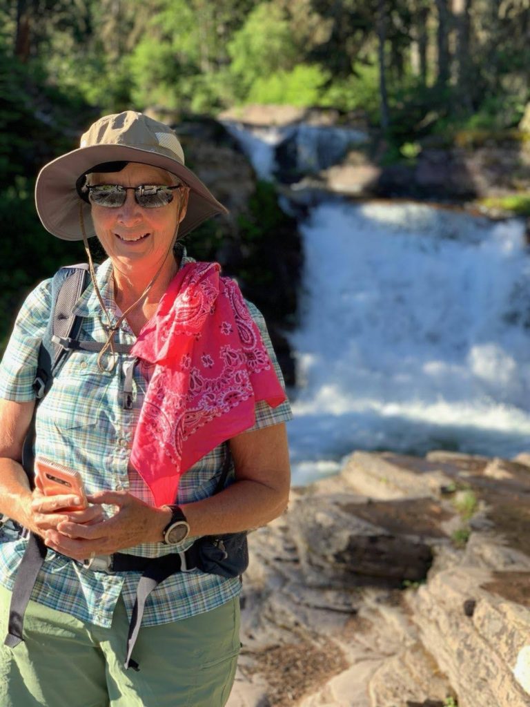 A woman in hiking gear standing next to a river