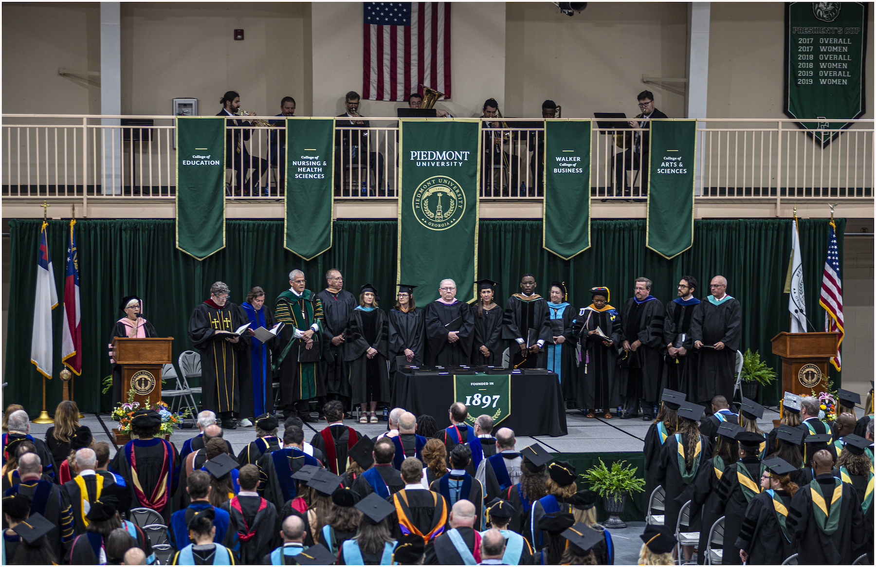 Professors and graduates and standing during graduation ceremony.