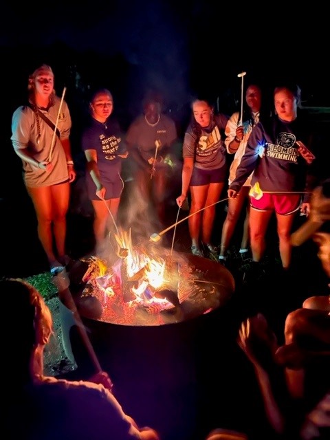 Students roasting marshmallows over campfire.