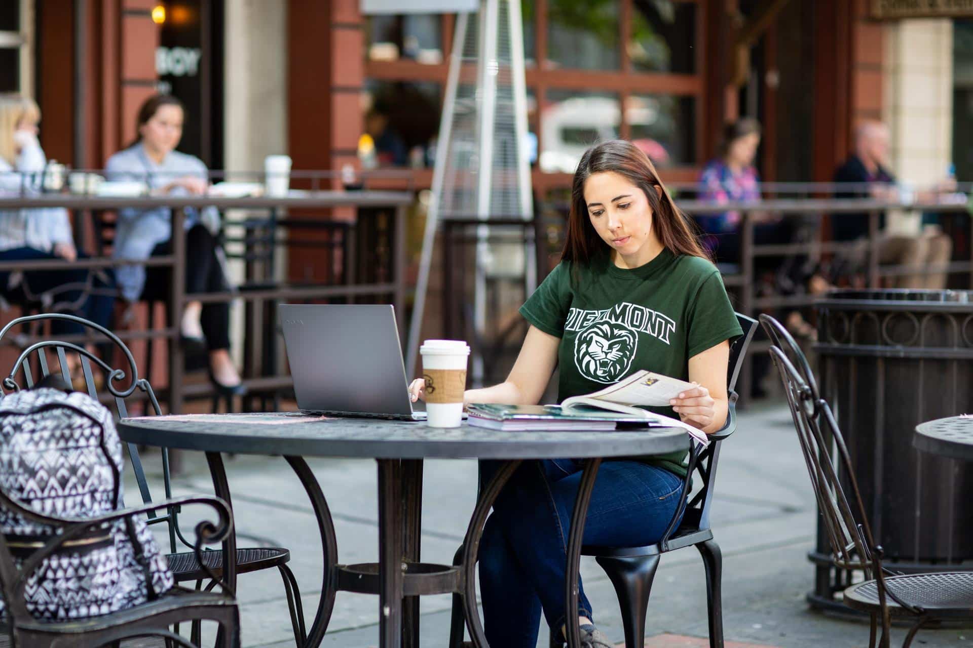 Young woman studying at a table with a coffee and laptop