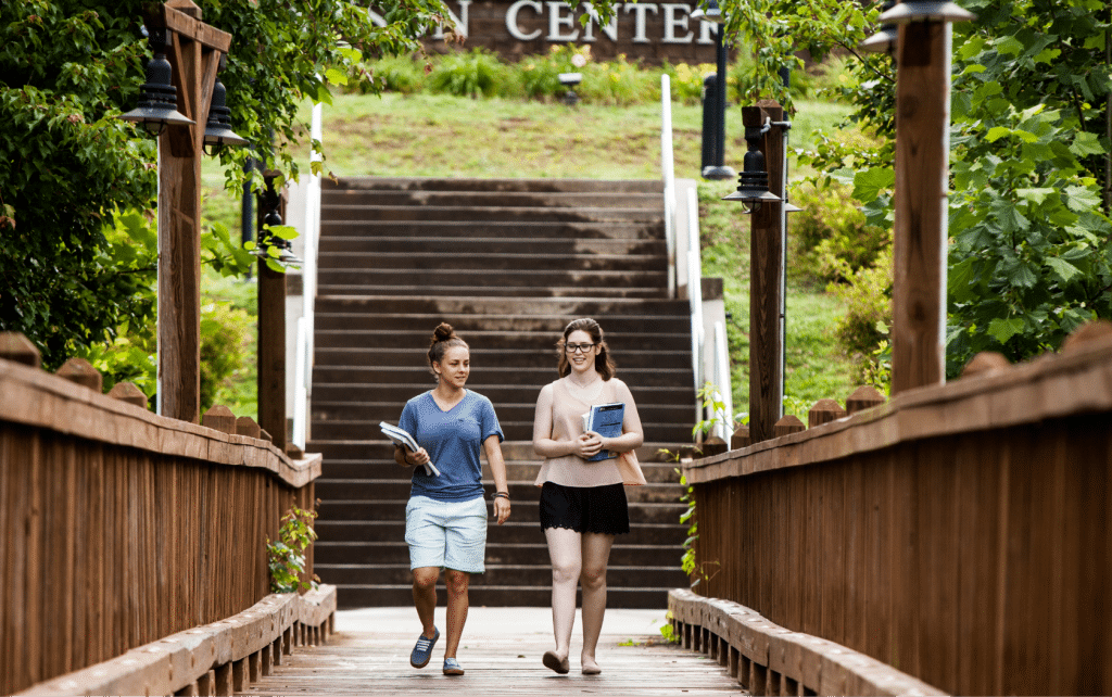 Two young women walking across a wooden bridge