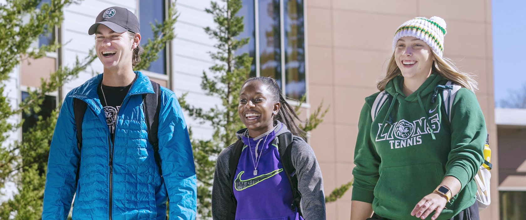 Three students smiling as the walk along campus