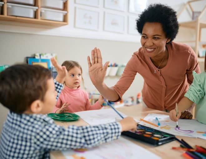 art teacher high fiving an elementary school student in an art class