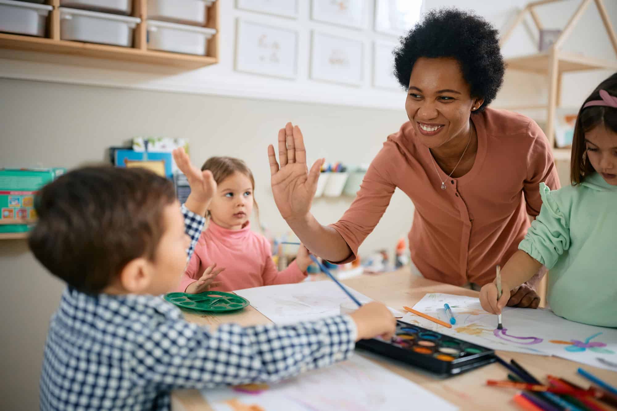 art teacher high fiving an elementary school student in an art class