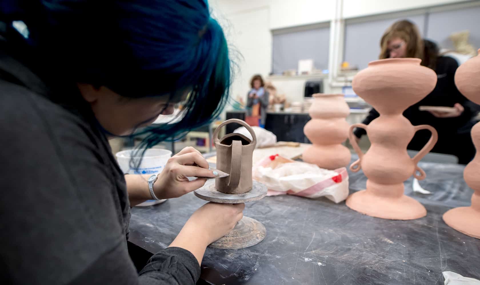 art students in classroom working on pottery