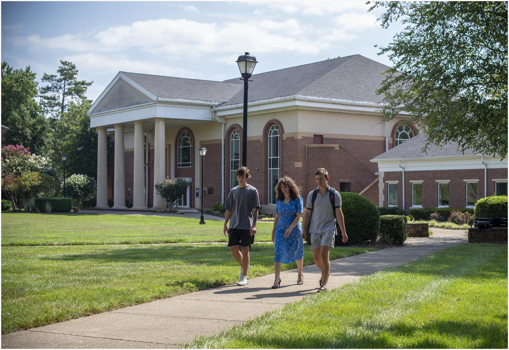 Three people walking down a pathway on campus