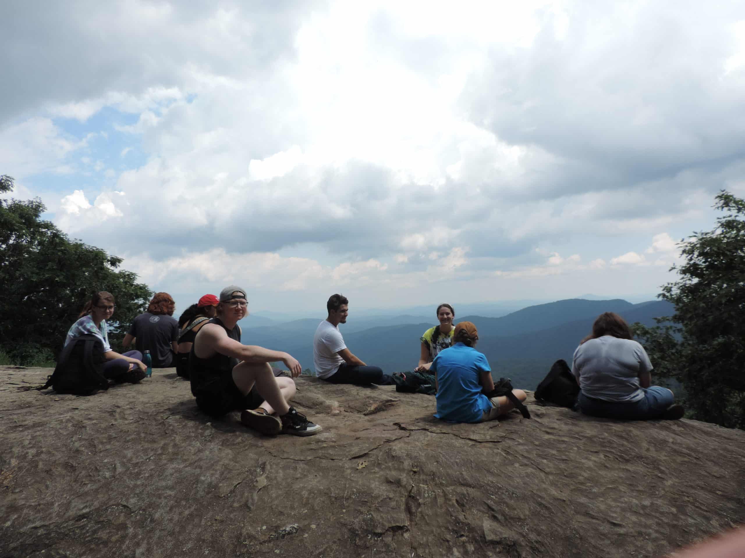 Group of students sitting on a mountain top, overlooking the Blue Ridge Mountains