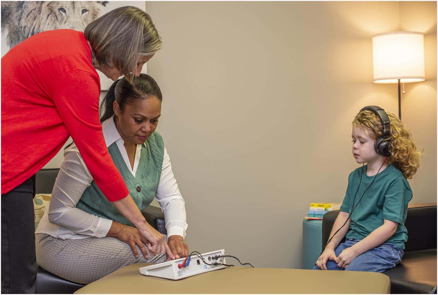 Two women working with a child to complete a hearing test.
