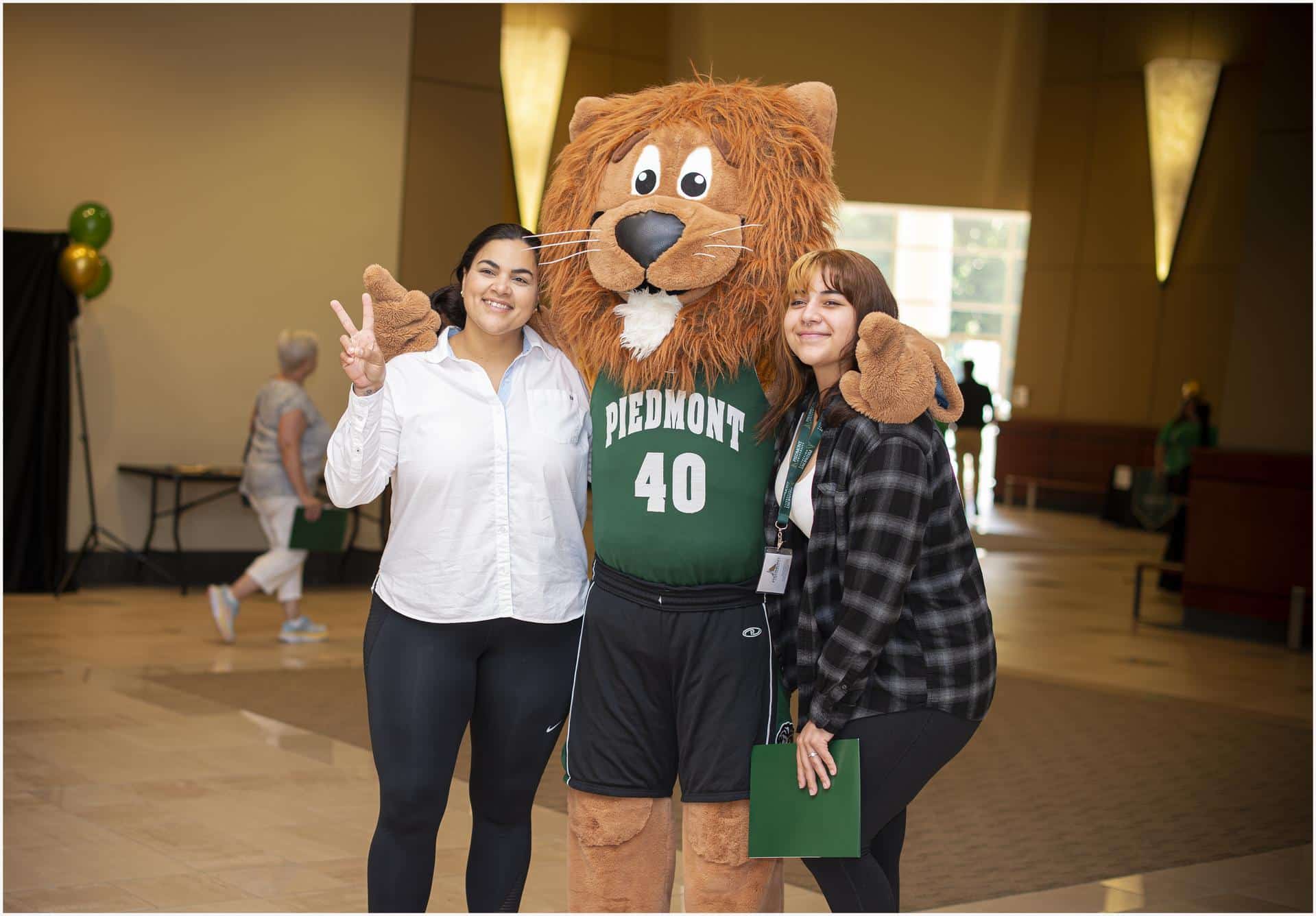Piedmont lion mascot posing with two young women