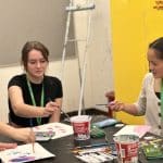 Three young women painting at a table