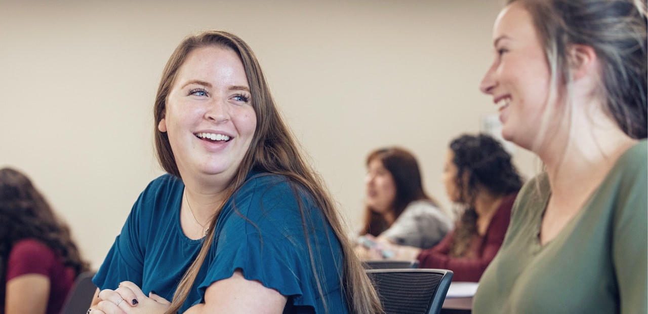 Two young women smiling in class