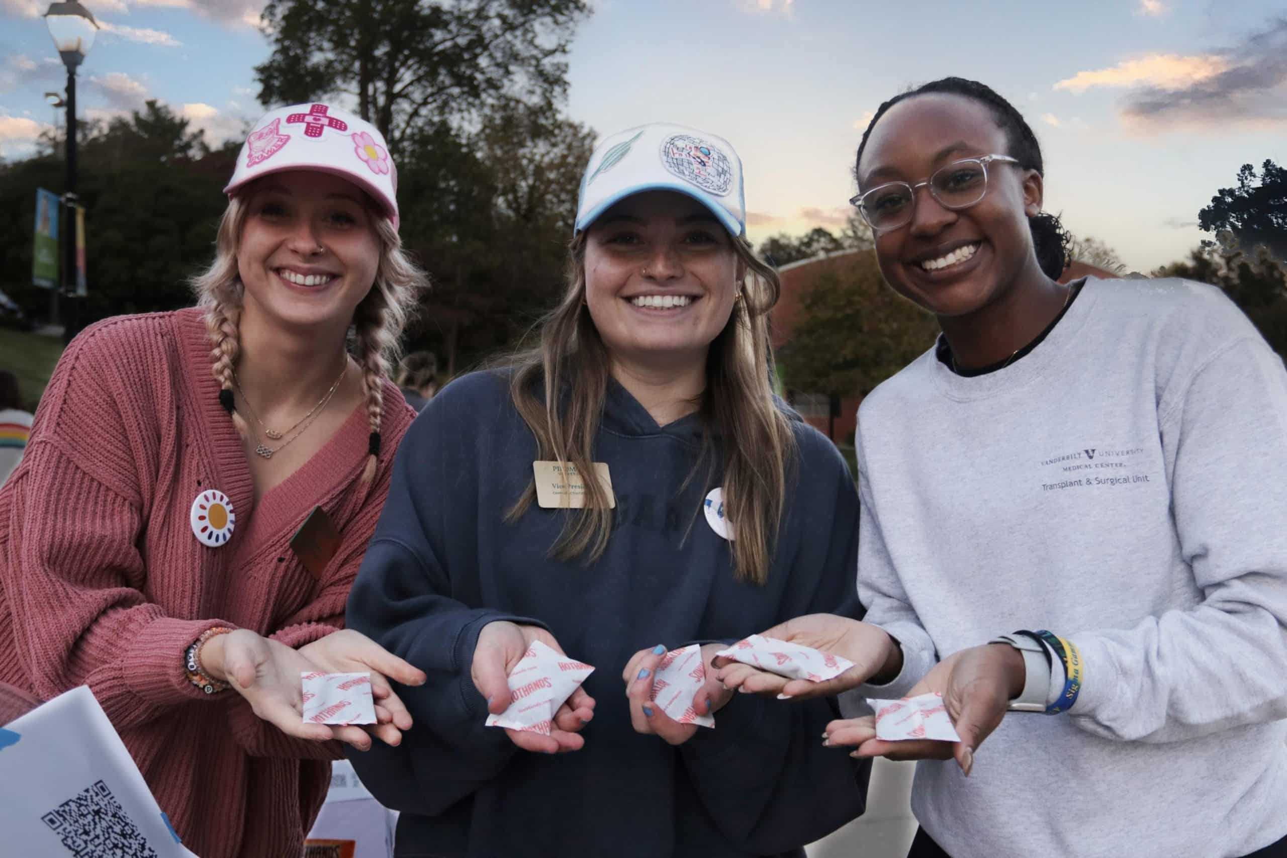 Three women holding "Hot Hands" hand warmers
