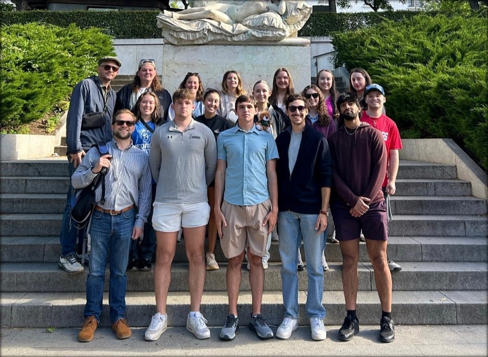 A group of travel abroad students posing in front of a statue