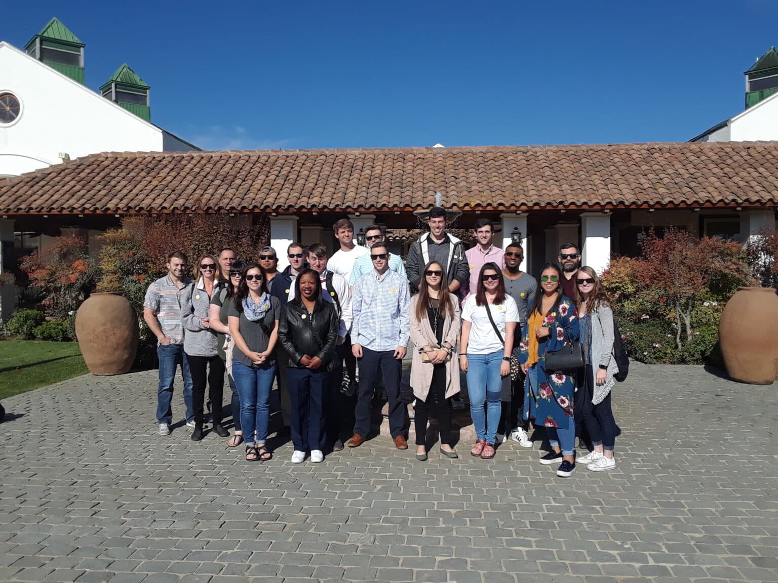 Group of young men and women standing in front of a Spanish style building