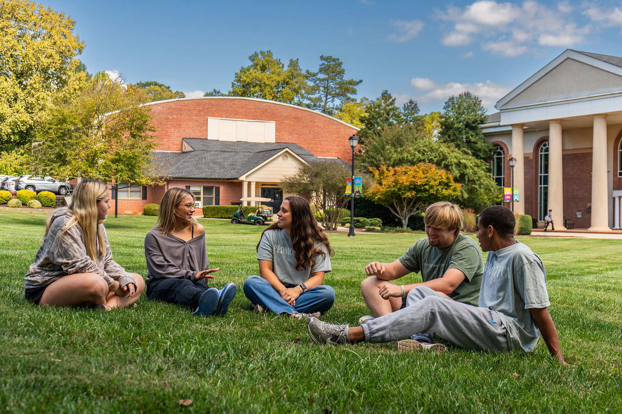 A group of students enjoying a beautiful day outside, sitting on an open lawn on the Piedmont campus.